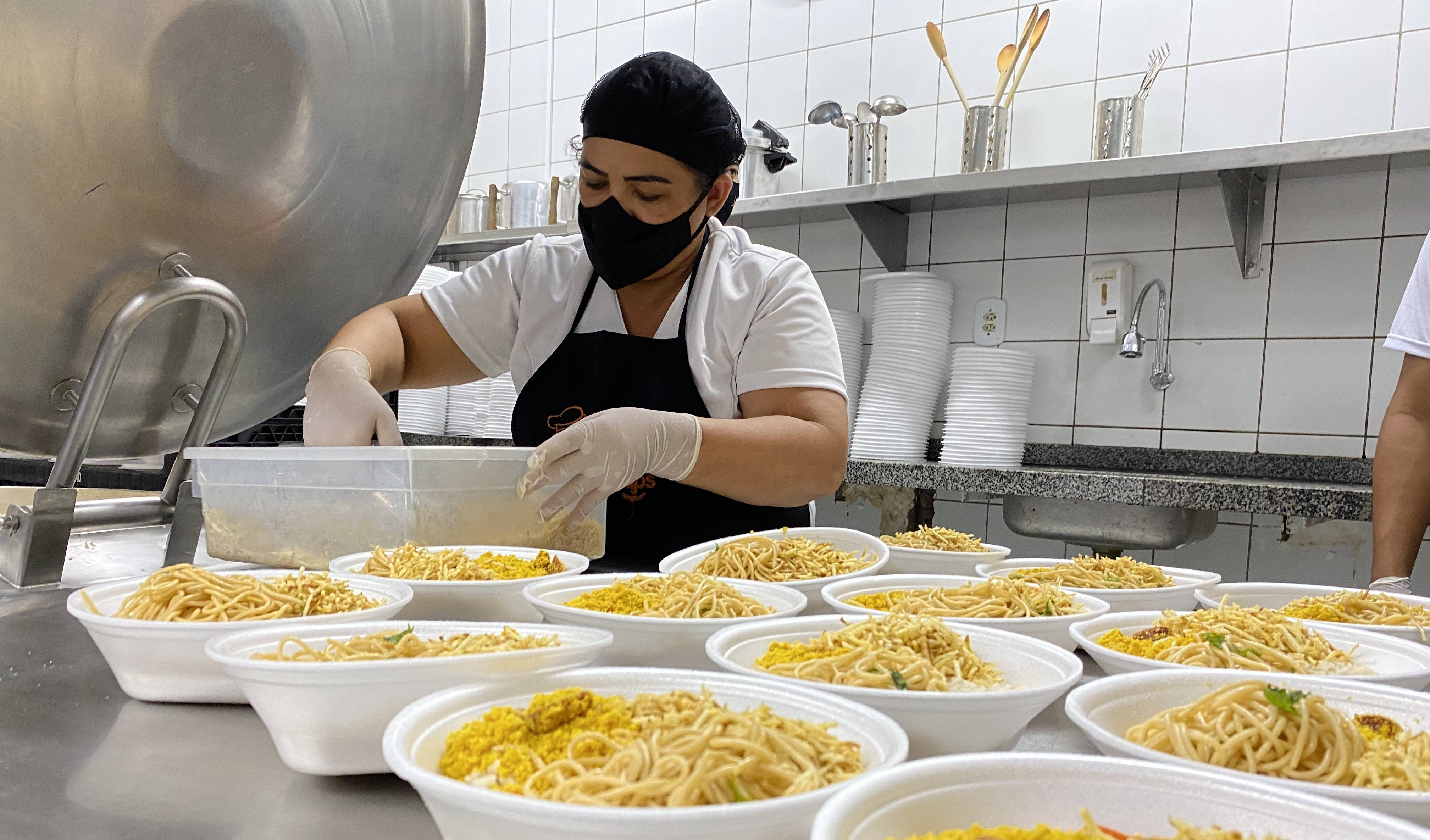 uma cozinheira na frente de várias quentinhas